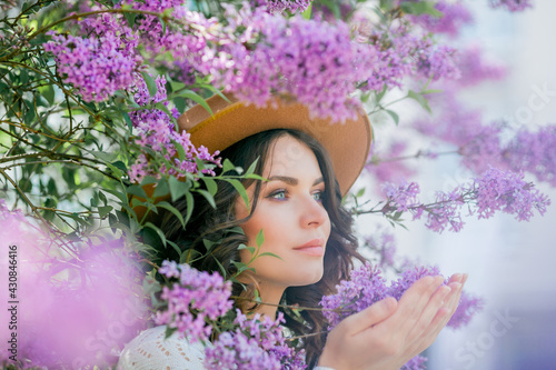 Portrait of a beautiful young woman in a blooming lilac park. Purple flowers. Spring. Happiness.