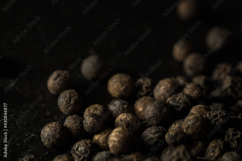 Close up of group of dried peppercorns in lower right corner on slate plate Close up of group of dried peppercorns in lower right corner on slate plate
