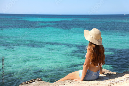 Longing for summer, longing for holidays. Back view on female tourist enjoying view crystalline water of the ocean. © zigres