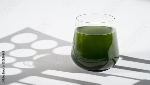 Healthy spirulina chlorella drink in the glass hard light with shadows. Superfood, detox drink. Healthy care, healthy eating concept. photo