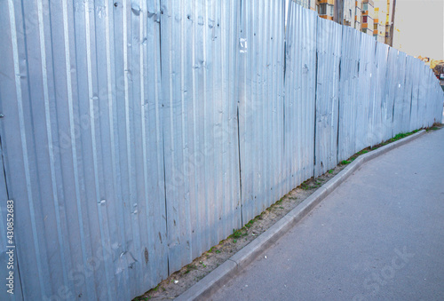 A metal fence along the sidewalk. Fences of the construction site. enclosure, fencing, guard © O.PASH