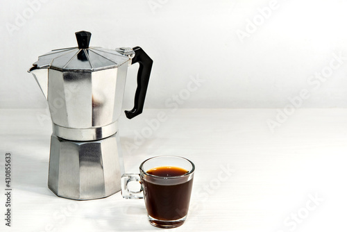 Italian coffee maker with espresso coffee on white wooden table.