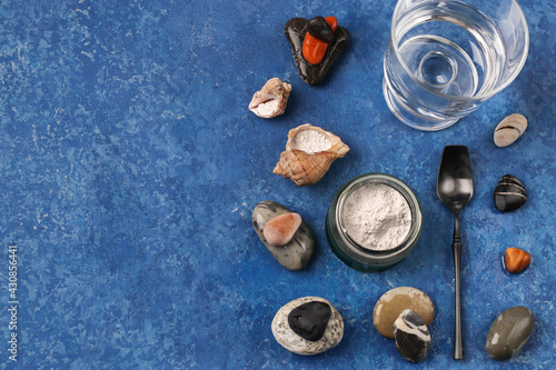 Healthy lifestyle concept. Hydrolyzed marine collagen powder in a glass jar and a glass of clean water among the stones on a blue background. Natural supplement. Copy space.