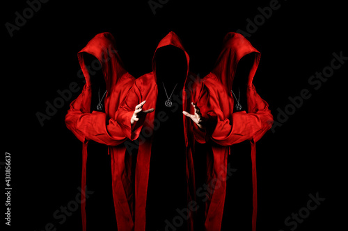 Mystery three sectarians in a red hooded cloaks in the dark. Unrecognizable person. Hiding face in shadow. Conspiracy concept.  © raland