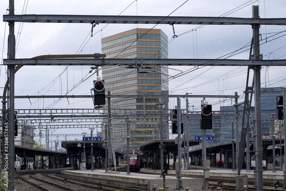 Fototapeta premium Railway station Zurich Oerlikon with skyscraper Andreasturm (Andreas tower) in the background. Photo taken April 29th, 2021, Zurich, Switzerland.