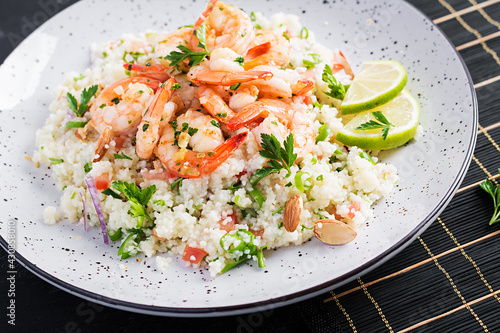 Couscous with roasted shrimps, tomatoes, red onions, almond nuts and parsley. Moroccan food with couscous and prawns.