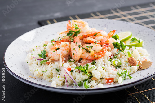 Couscous with roasted shrimps, tomatoes, red onions, almond nuts and parsley. Moroccan food with couscous and prawns.
