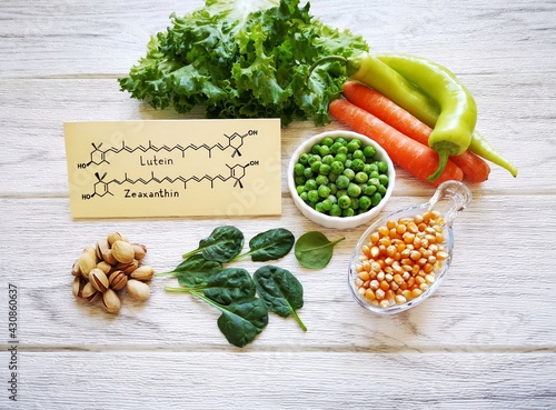 Foods rich in lutein and zeaxanthin with structural chemical formulas of two carotenoids. Fresh vegetable as best food sources of lutein and zeaxanthin. Spinach, carrot, peas, corn, pepper, lettuce. photo