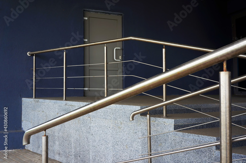 Porch steps and railing in front of door of entrance in modern building.