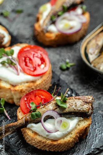 Sandwich with sprats and tomatoes on white plate. Danish cuisine. Food recipe background. Close up. vertical image