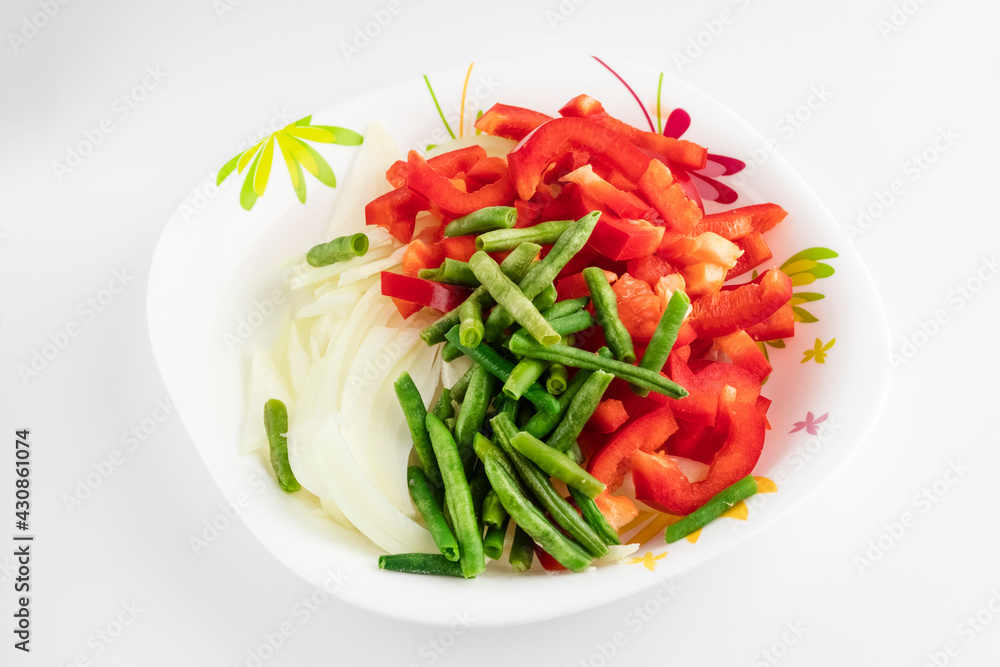 Cutting fresh vegetables in a white plate on a light background. Ingredients for cooking Cutting fresh vegetables in a white plate on a light background. Ingredients for cooking