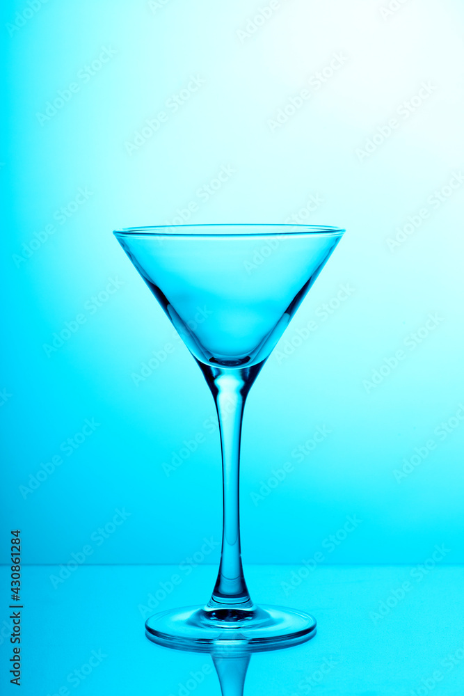 Studio photo of empty transparent martini glass on light blue background. Silhouette of triangular shape glass for coctails Studio photo of empty transparent martini glass on light blue background. Silhouette of triangular shape glass for coctails