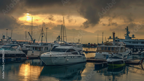 White yachts and boats in the sea harbor of the Russian resort on the Black Sea against the backdrop of a beautiful sunset sky