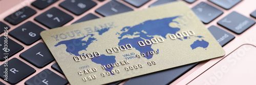 Credit bank card lying on laptop keyboard closeup
