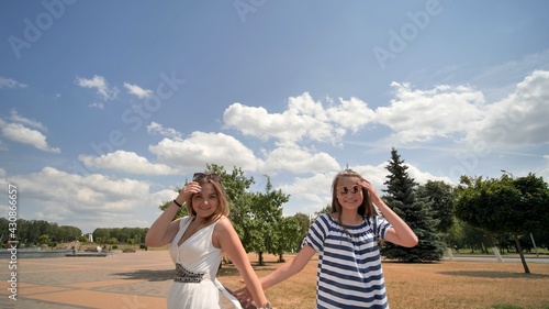 Cheerful girls are walking together on a sunny day.