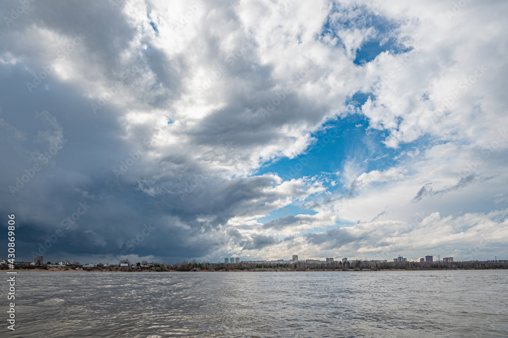 Panoramic landscape, a thundercloud over the Kama River in the city of Perm, gray storm clouds cover the blue sky.
