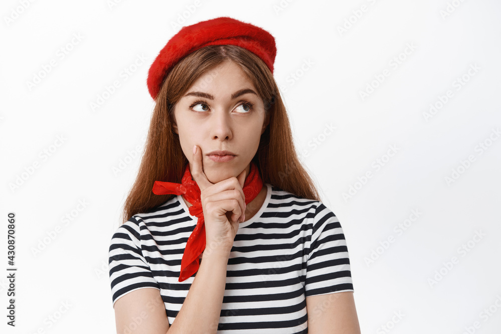 Close up of thoughtful girl student in french beret thinking of solution, looking aside with pensive face, standing over white background Close up of thoughtful girl student in french beret thinking of solution, looking aside with pensive face, standing over white background