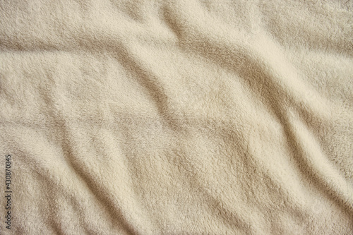Fluffy gentle pastel biege fabric with waves and folds. Soft pastel textile texture.