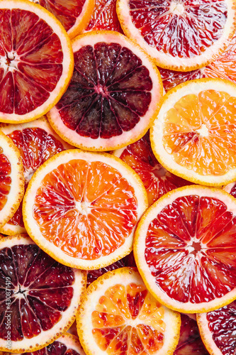 Bright colorful background of fresh ripe sliced blood oranges. Close up, flat lay, top view. Blood orange texture