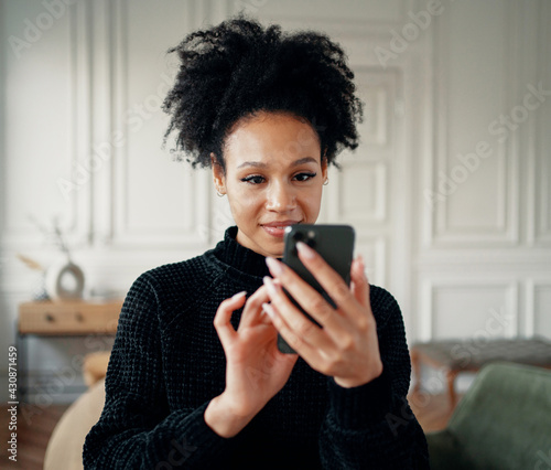 A smart student makes an order in an online store through the app. Surfs the Internet looking for a ticket. A woman of African American appearance smiles sends an email to her phone.