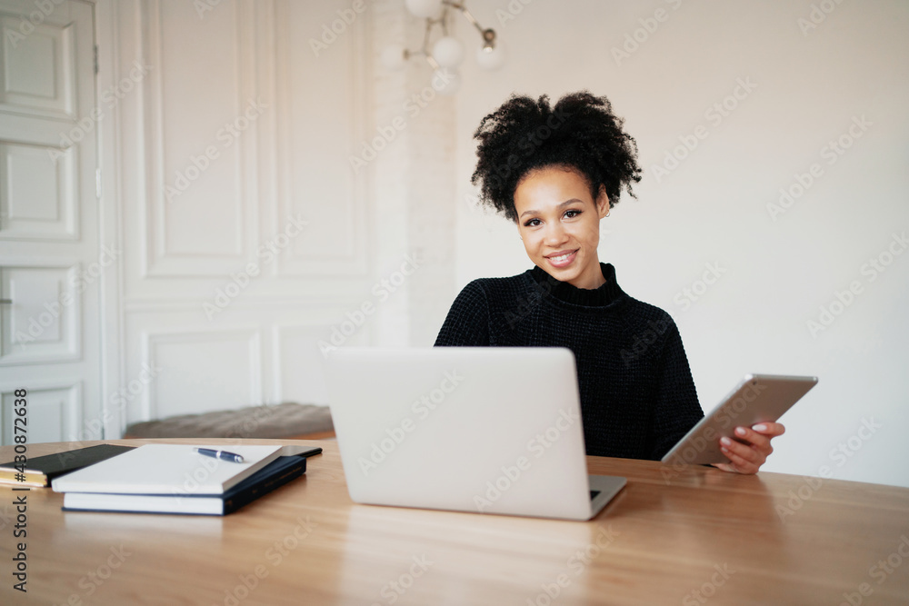 A contented woman of Afro appearance. A woman keeps online accounting of expenses for a month at home. Records costs in a convenient app. A contented woman of Afro appearance. A woman keeps online accounting of expenses for a month at home. Records costs in a convenient app.