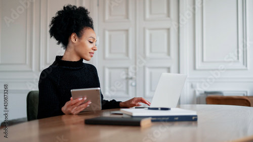 The manager prints the text on the computer laptop. In his hands, he holds a tablet with statistics about the new project. A smiling woman works online from an office in a coworking space.