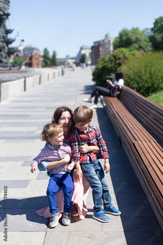 Happy mother with her children spends time in city park