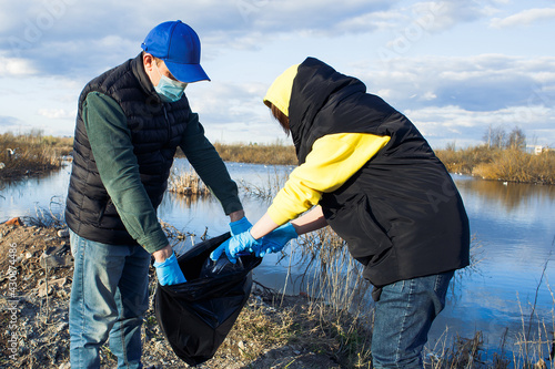 volunteers collect plastic bottles in bags on the river bank, the concept of ecology and land protection