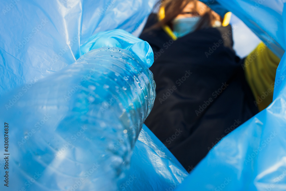 a woman throws a plastic bottle into a bag under the garbage, close-up, the concept of ecology and protection of the earth