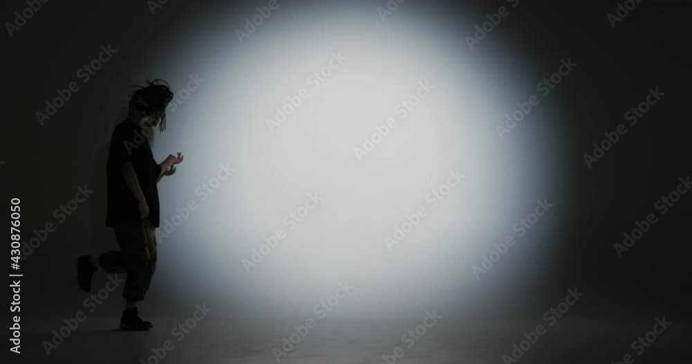 Dancing young girl performing fiery hip hop dance to music in spotlight. Contemporary dancer, rap youth culture Dancing young girl performing fiery hip hop dance to music in spotlight. Contemporary dancer, rap youth culture
