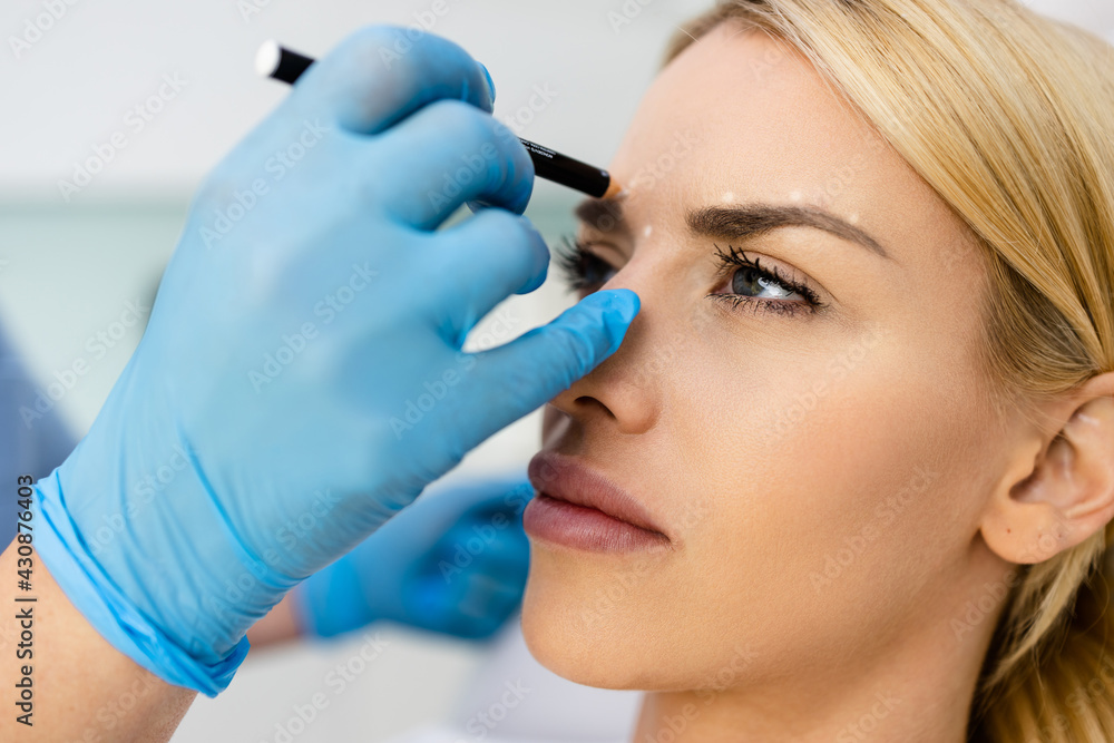 Beautiful young female patient with correction lines and dots on the face in an examination room. Beautiful young female patient with correction lines and dots on the face in an examination room.