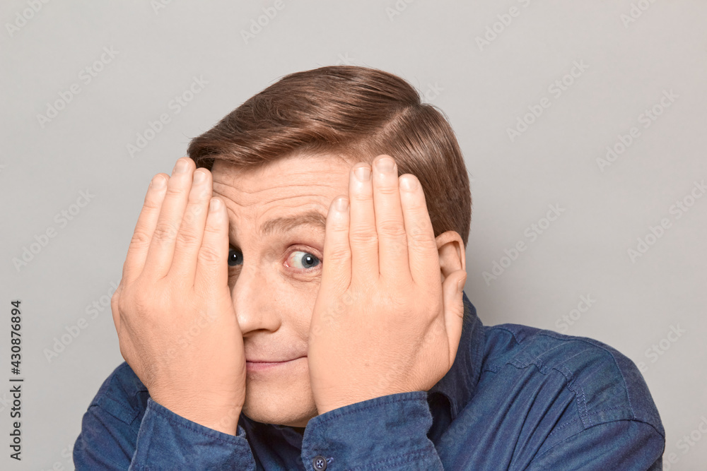 Portrait of happy man looking with one eye at something interesting Portrait of happy man looking with one eye at something interesting