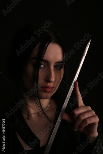 Brunette woman with a sword in shadows