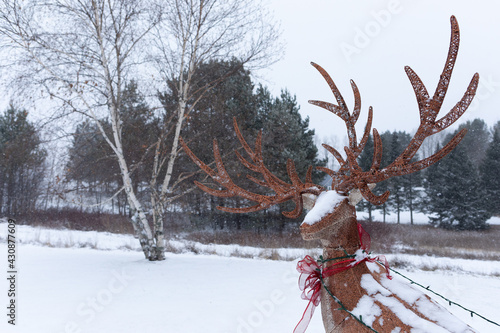 Deer figurine with holiday ribbon, standing in a snowy landscape in Maine. photo