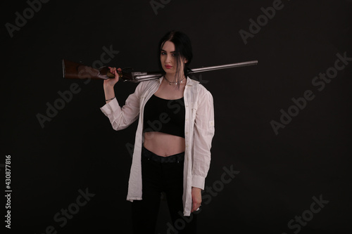 Brunette woman with vintage shotgun on black background