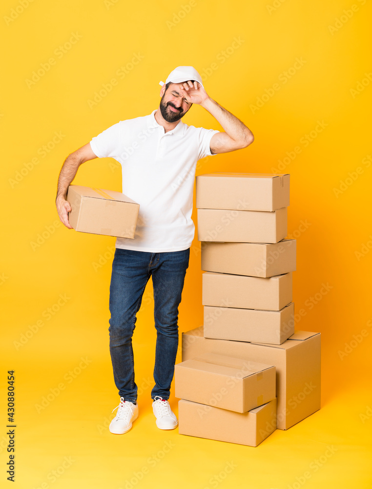 Full-length shot of delivery man among boxes over isolated yellow background with tired and sick expression Full-length shot of delivery man among boxes over isolated yellow background with tired and sick expression