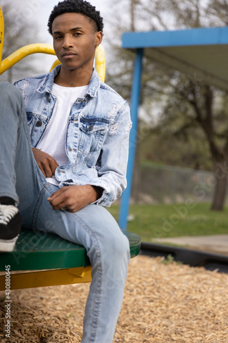 Portrait of a Young Male African American Teen Model Outdoors at the Park Sitting on a Carousel