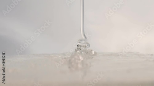 A trickle of clear cosmetic gel with tiny bubbles drips onto the surface. facial serum, anti-aging cream, hair shampoo, antibacterial gel, hyaluronic acid
