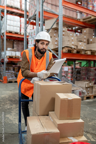 Bearded warehouse worker examining papers