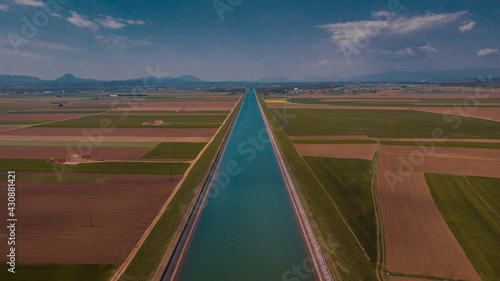 Beautiful blue waterway canal of hydroelectric power plant between the fields on the Drava plains in Slovenia. Aerial view of a water canal.