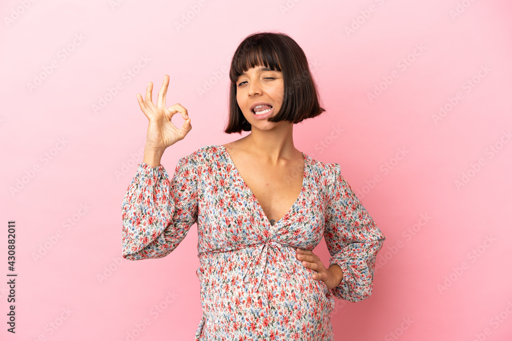 Young pregnant woman over isolated pink background showing ok sign with fingers Young pregnant woman over isolated pink background showing ok sign with fingers