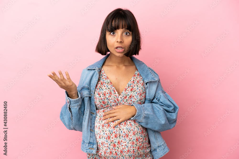 Young pregnant woman over isolated pink background making doubts gesture Young pregnant woman over isolated pink background making doubts gesture