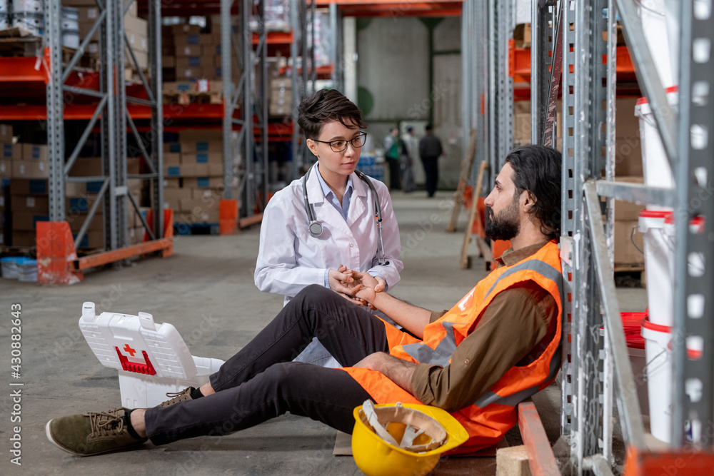 Fototapeta premium Checking pulse of warehouse mover dropped on floor