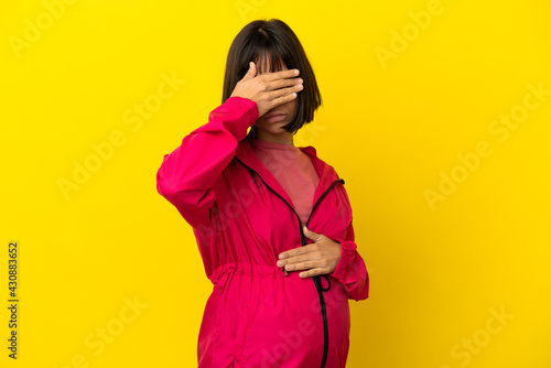 Young pregnant woman over isolated yellow background covering eyes by hands. Do not want to see something © luismolinero