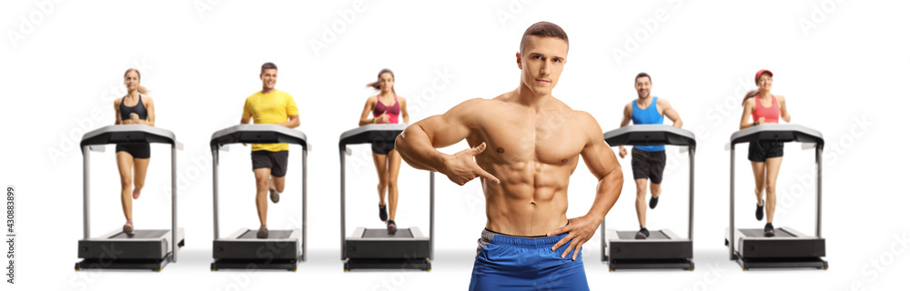 Obraz premium Topless muscular bodybuilder posing in front of people running on treadmills