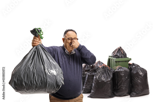 Mature man throwing a smelly waste bag in a bin photo