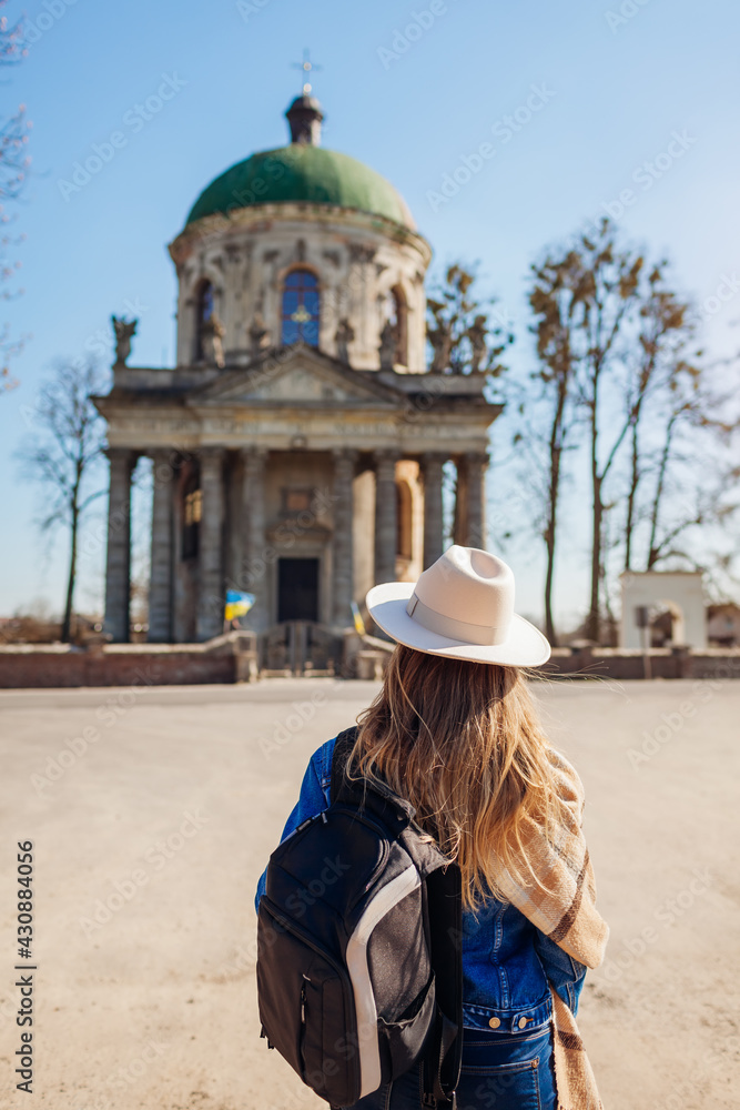 Tourist looking at ancient Roman Catholic church of saint Joseph in Pidhirtsi, Ukraine. Visiting architecture landmarks