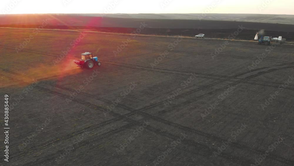 Tractor spreading artificial fertilizers in green field. Farmer fertilizing arable land with nitrogen and potassium fertilizer. Tractor spreading artificial fertilizers in green field. Farmer fertilizing arable land with nitrogen and potassium fertilizer.