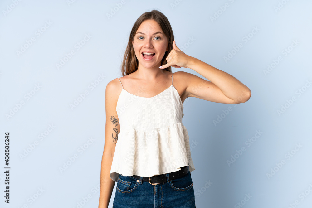 Young Lithuanian woman isolated on blue background making phone gesture. Call me back sign Young Lithuanian woman isolated on blue background making phone gesture. Call me back sign