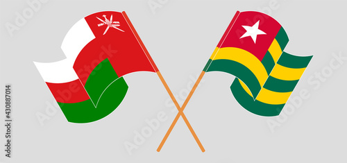 Crossed and waving flags of Oman and Togo